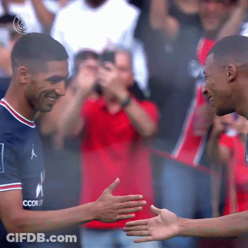 Two Soccer Players Are Shaking Hands In Front Of A Crowd And One Of Their Shirts Says Coor GIF