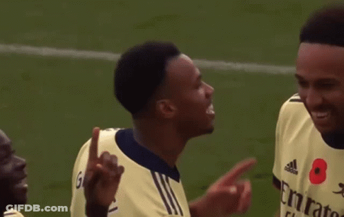 Two Soccer Players Are Talking To Each Other On The Field . One Of The Players Has A Poppy On His Shirt . GIF