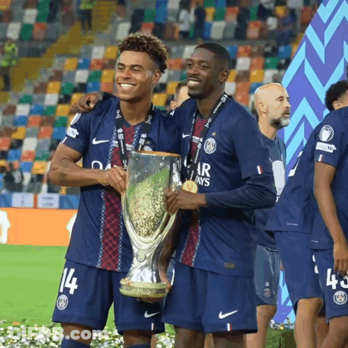 Two Soccer Players Holding A Trophy And One Has The Number 14 On His Shirt GIF