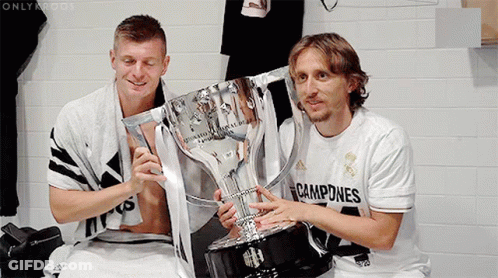Two Soccer Players Holding A Trophy With The Word Campeones On Their Shirt GIF