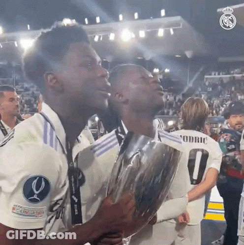 Two Soccer Players Holding Trophy With Number 0 GIF