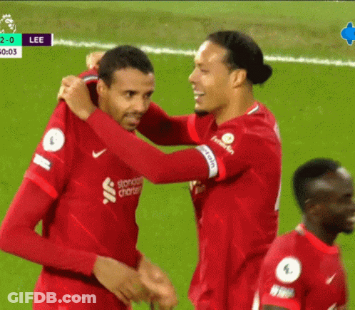 Two Soccer Players Hugging In Standard Charter Jerseys GIF