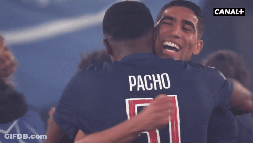 Two Soccer Players Hugging With The Name Pacho On The Back Of Their Shirt GIF