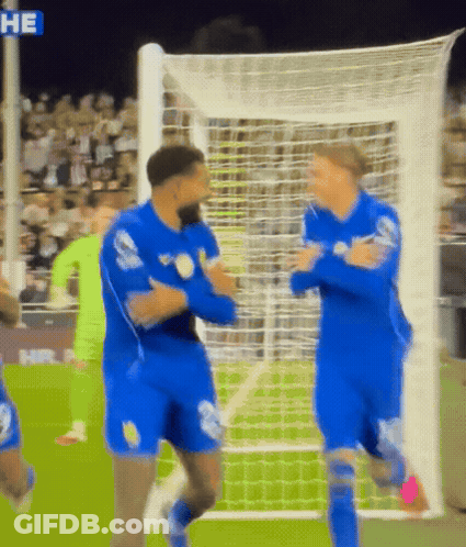 Two Soccer Players In Blue Uniforms Hugging In Front Of Net Saying He GIF