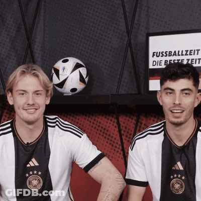 Two Soccer Players Next To Fussballzeit Sign GIF