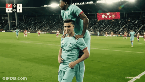 Two Soccer Players On A Field With A Scoreboard In The Background That Says 1318 GIF