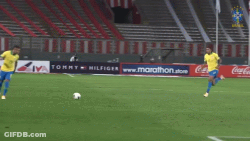 Two Soccer Players On Field With Tommy Hilfiger Ad GIF