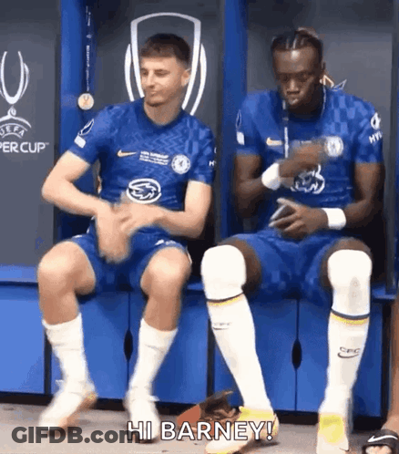 Two Soccer Players Sitting On Locker Room Bench One Talking GIF