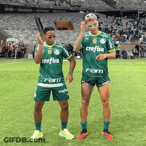 Two Soccer Players Wearing Green Crefisa Jerseys Are Dancing On A Field GIF