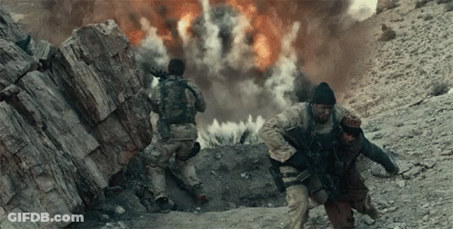Two Soldiers Are Running In Front Of An Explosion In The Desert GIF