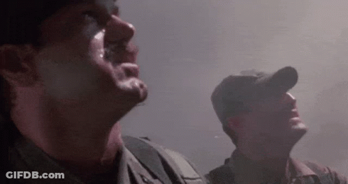 Two Soldiers Are Standing Next To Each Other In A Dark Room Looking Up At The Sky . GIF
