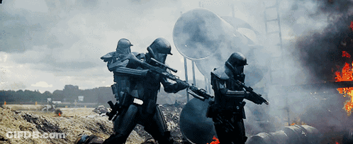 Two Soldiers Holding Guns In Front Of Burning Building With Letter M On Helmets GIF