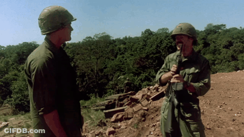 Two Soldiers In Front Of A Thatched Hut With Explosion GIF