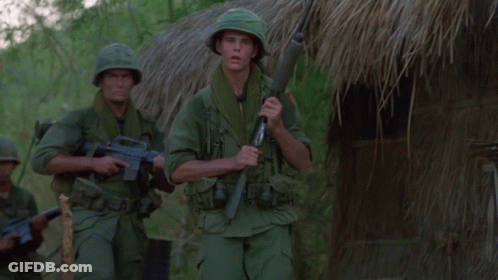 Two Soldiers In Front Of Thatched Hut With Explosion GIF