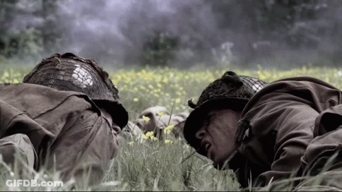 Two Soldiers Laying In A Field With One Wearing A Helmet That Says Us Army GIF