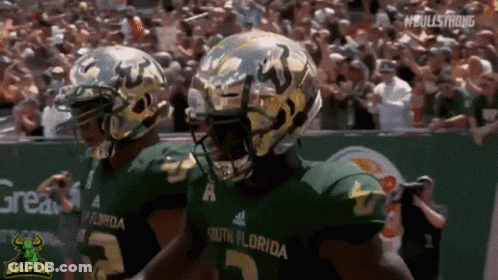 Two South Florida Football Players Are Walking On The Field During A Game GIF