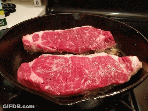 Two Steaks Are Being Cooked In A Cast Iron Skillet GIF