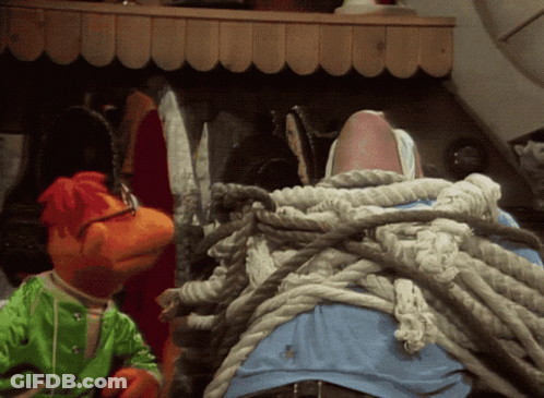 Two Stuffed Animals Are Tied Up With Ropes And One Is Wearing A Green Shirt GIF