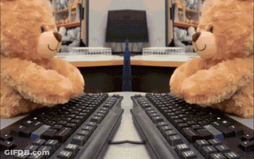 Two Teddy Bears Are Hugging Each Other While Using A Computer Keyboard GIF
