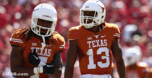 Two Texas Football Players Wearing Orange Uniforms Are Standing Next To Each Other GIF