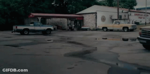 Two Trucks Parked In Front Of Building Saying American Union Post GIF