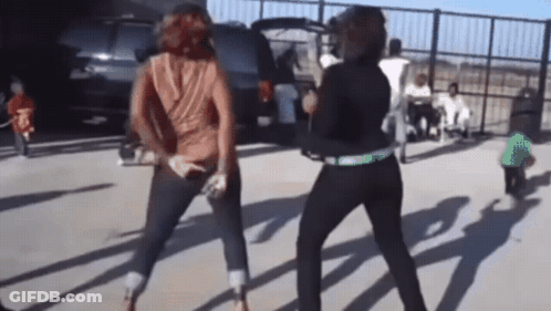 Two Women Are Dancing In A Parking Lot In Front Of A Suv GIF