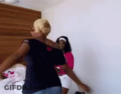 Two Women Are Dancing In A Room With A Wooden Headboard In The Background . GIF