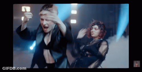 Two Women Are Dancing In Front Of A Blue Light . GIF