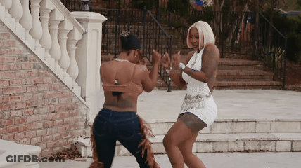 Two Women Are Dancing In Front Of A Staircase GIF