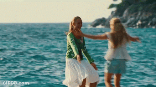 Two Women Are Dancing In The Ocean And Hugging Each Other GIF