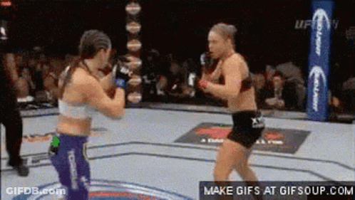 Two Women Are Fighting In A Boxing Ring In Front Of A Crowd Of People . GIF