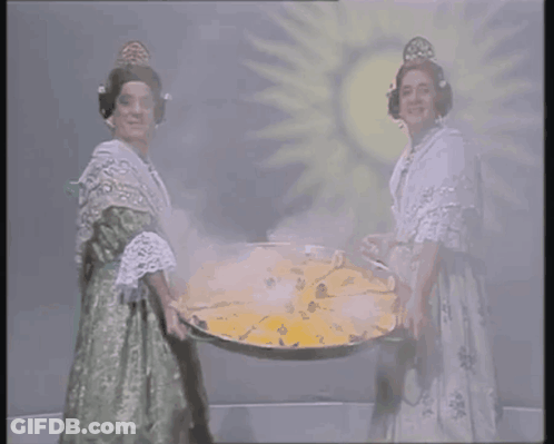 Two Women Are Holding A Large Tray Of Food In Front Of A Sun GIF