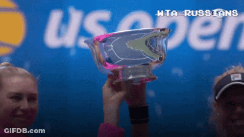 Two Women Are Holding A Trophy In Front Of A Sign That Says Us Open GIF