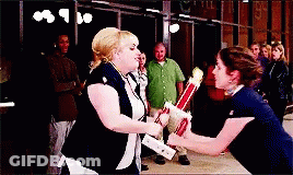 Two Women Are Holding Trophies In Front Of A Group Of People GIF
