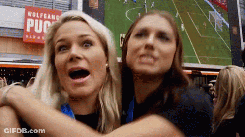 Two Women Are Hugging Each Other In Front Of A Sign That Says Wolfgang Pub GIF