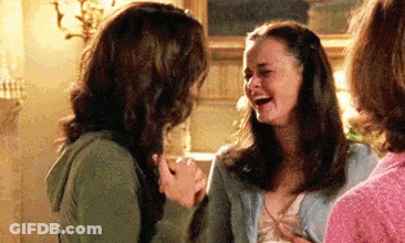 Two Women Are Laughing Together In A Living Room While Holding Hands . GIF