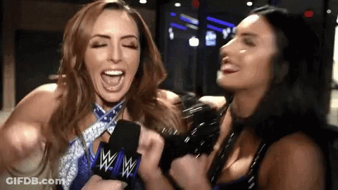 Two Women Are Laughing While Holding A Microphone With The W Logo On It GIF