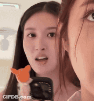 Two Women Are Looking At Each Other And One Is Holding A Cat Toy GIF