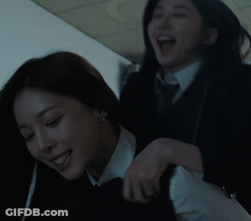 Two Women Are Playing With Each Other In A Dark Room And One Is Smiling GIF
