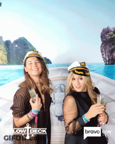 Two Women Are Posing For A Photo In Front Of A Bravo Con Poster GIF
