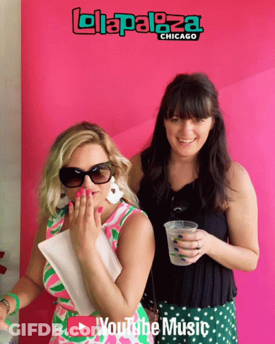Two Women Are Posing For A Photo In Front Of A Pink Background That Says Lollapaloza Chicago GIF