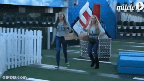 Two Women Are Running In Front Of A Sign That Says Milele GIF