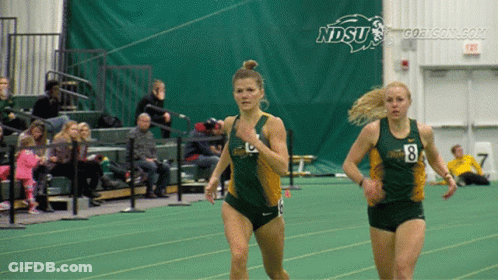 Two Women Are Running On A Track With Ndsu Written On The Wall Behind Them GIF