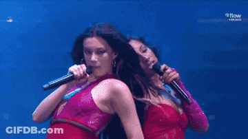 Two Women Are Singing Into Microphones On A Stage With Samsung In The Background GIF