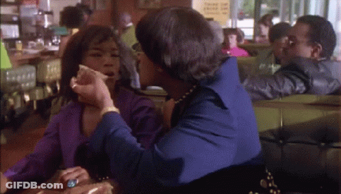 Two Women Are Sitting At A Table In A Diner Talking GIF