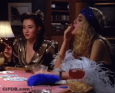 Two Women Are Sitting At A Table Smoking Cigarettes GIF