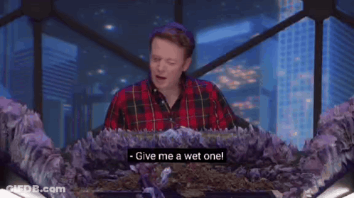 Two Women Are Sitting At A Table Talking To Each Other And One Of Them Says Give Me A Wet One . GIF