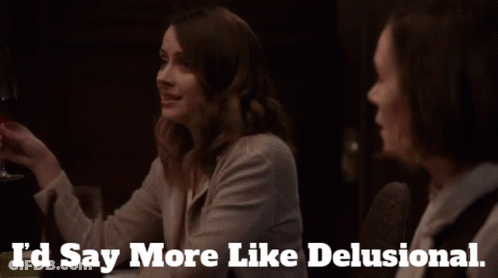 Two Women Are Sitting At A Table With The Words I 'D Say More Like Delusional GIF