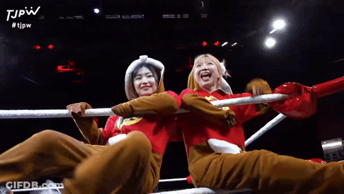 Two Women Are Sitting In A Boxing Ring With The Tjpw Logo On The Bottom GIF