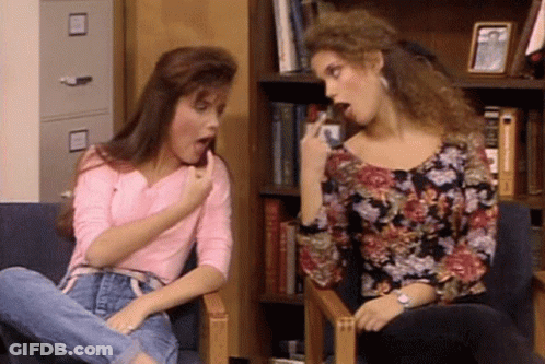 Two Women Are Sitting In Chairs With Their Mouths Open And One Is Pointing At The Other . GIF